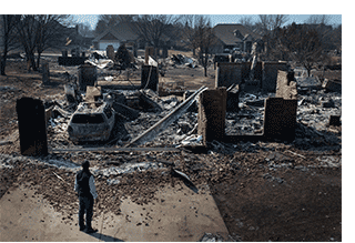 Person observing devastation to a home after a natural disaster