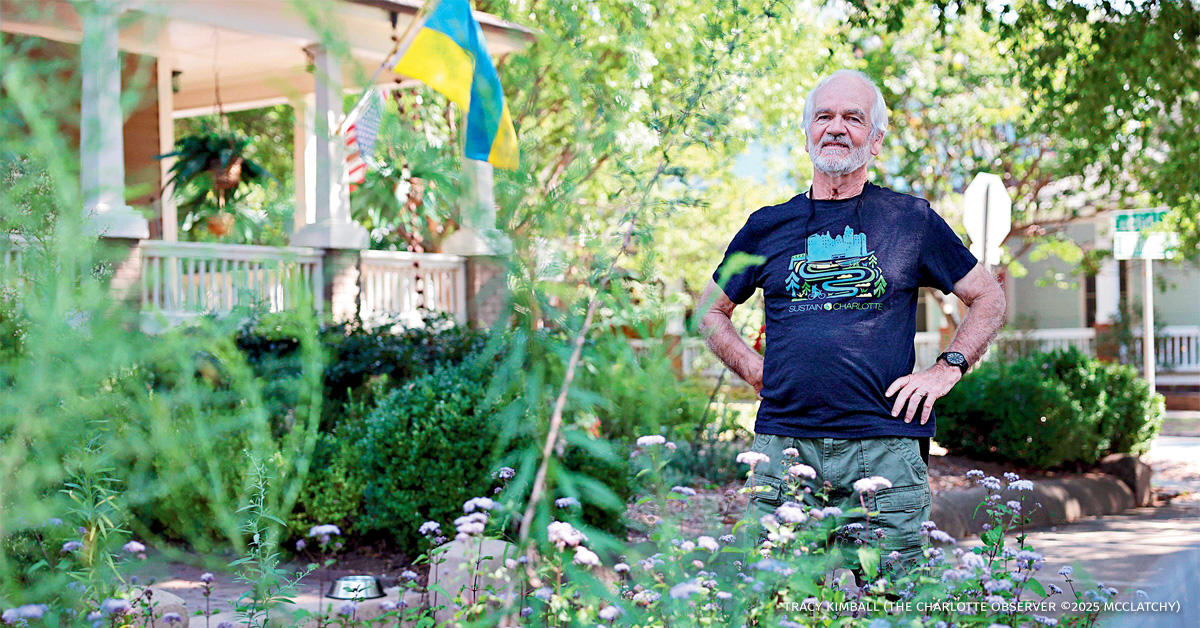 An image of Lou Lesesne standing in his front yard that has pollinating flowers.