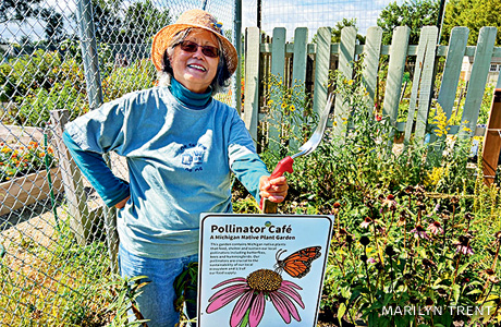 An image of a volunteer with a monarch habitat sign.
