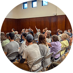 People sitting in folding chairs at community workshop
